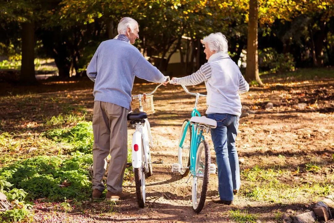 A man and woman holding hands while standing next to bikes.