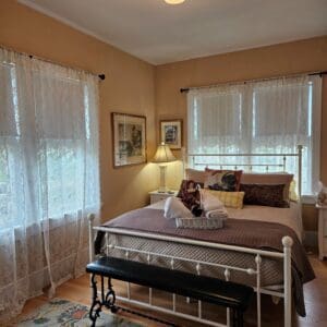 A bedroom with a bed, dresser and window.