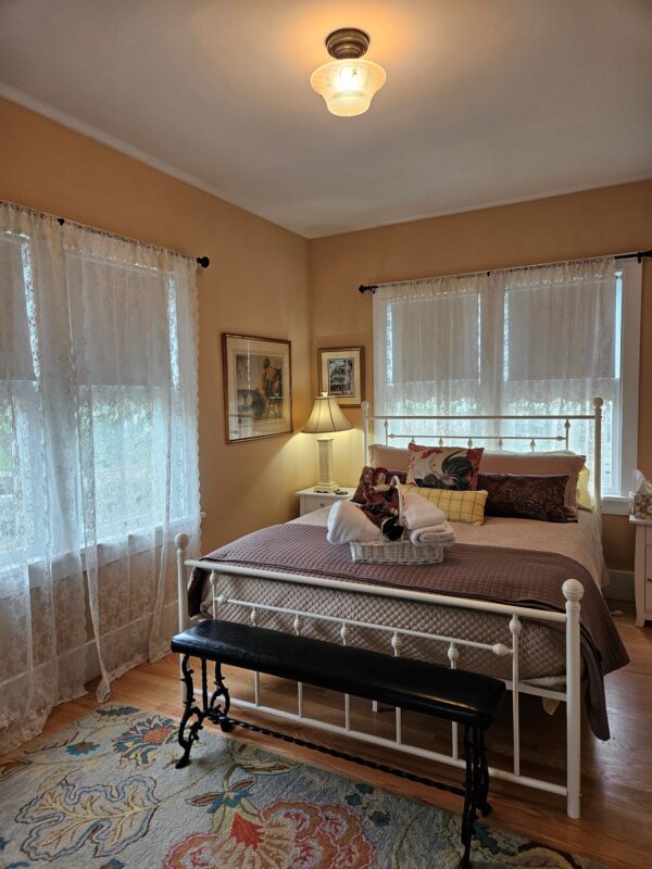 A bedroom with a bed, dresser and window.