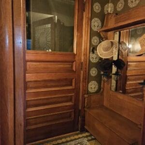 A wooden door with a mirror and a hat rack.