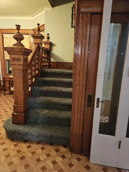 A staircase with wooden railings and green carpet.