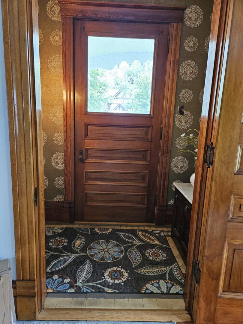 A door way with a window and rug in the floor.