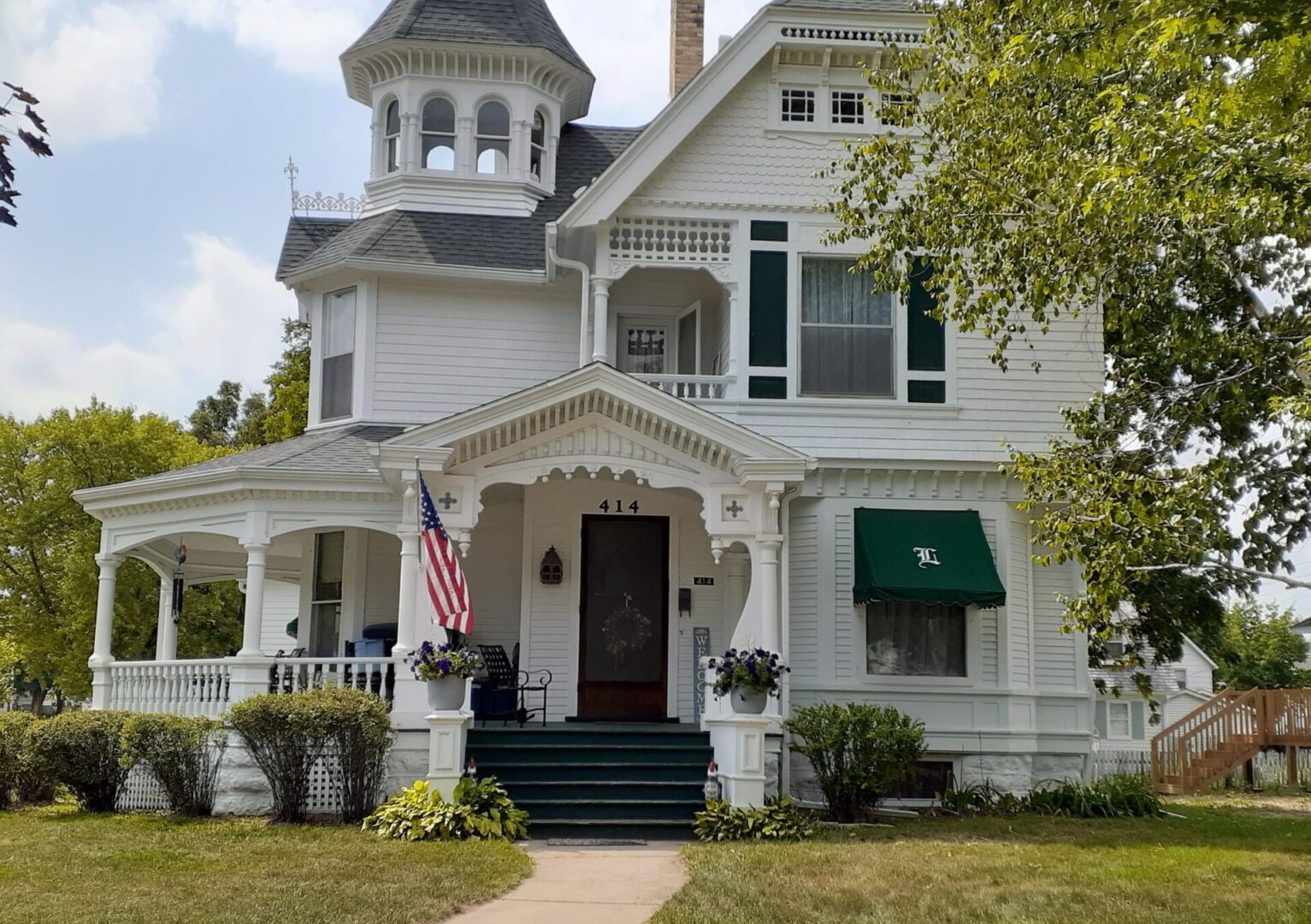 A large white house with an american flag on the front porch.